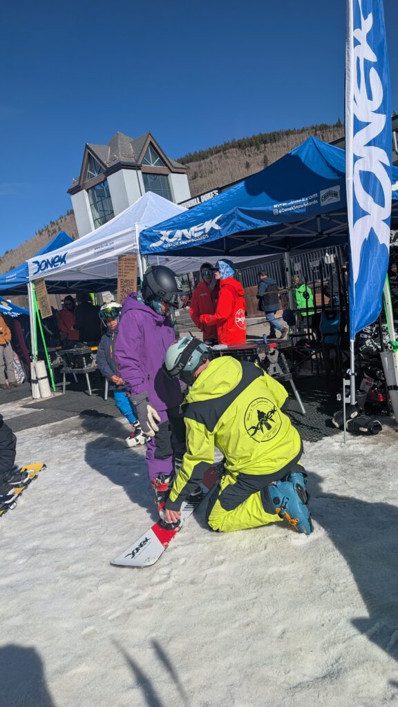 Donek employee setting rider on a alpine snowboard